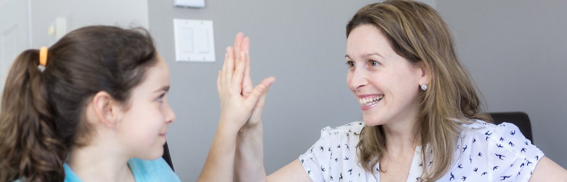 Mature mother helping her child with homework at home. Mädchen und Frau klatschen mit einer Hand ab